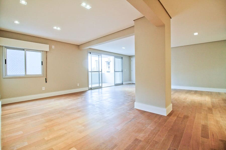Imagem do antes da reforma evidenciando o espaço vazio e a iluminação original próximo à varanda no projeto do apartamento na Vila Olímpia, São Paulo.